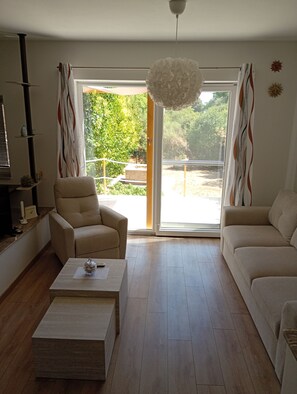A living room with a sofa, armchair, and coffee table. There is a sliding glass door leading to an outdoor area. - Stunning 100m² Modern Townhouse with Sea Views & Private Garden (Ližnjan)