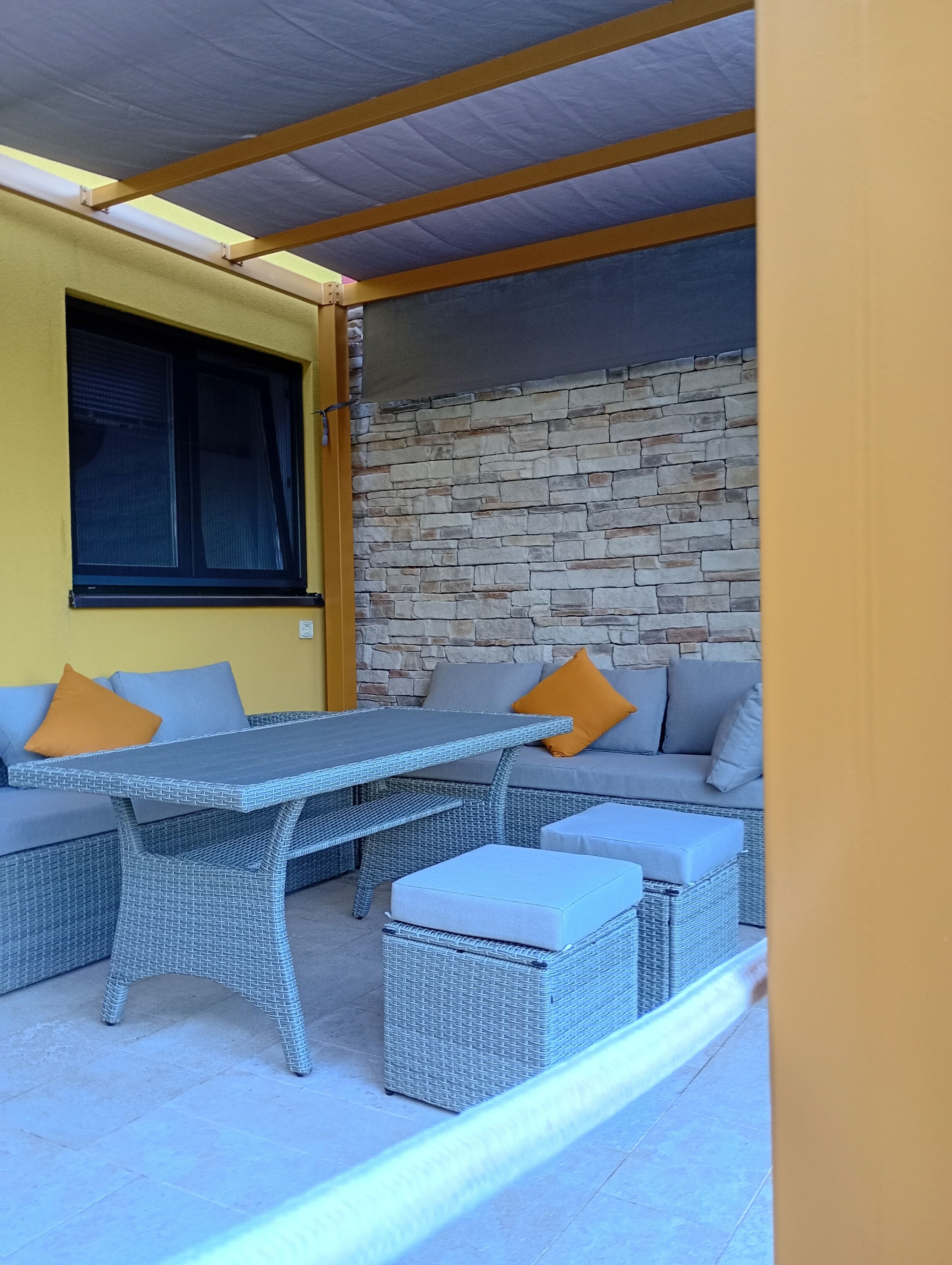 Un espace extérieur aménagé avec une table et des chaises, un canapé et un mur en pierre.