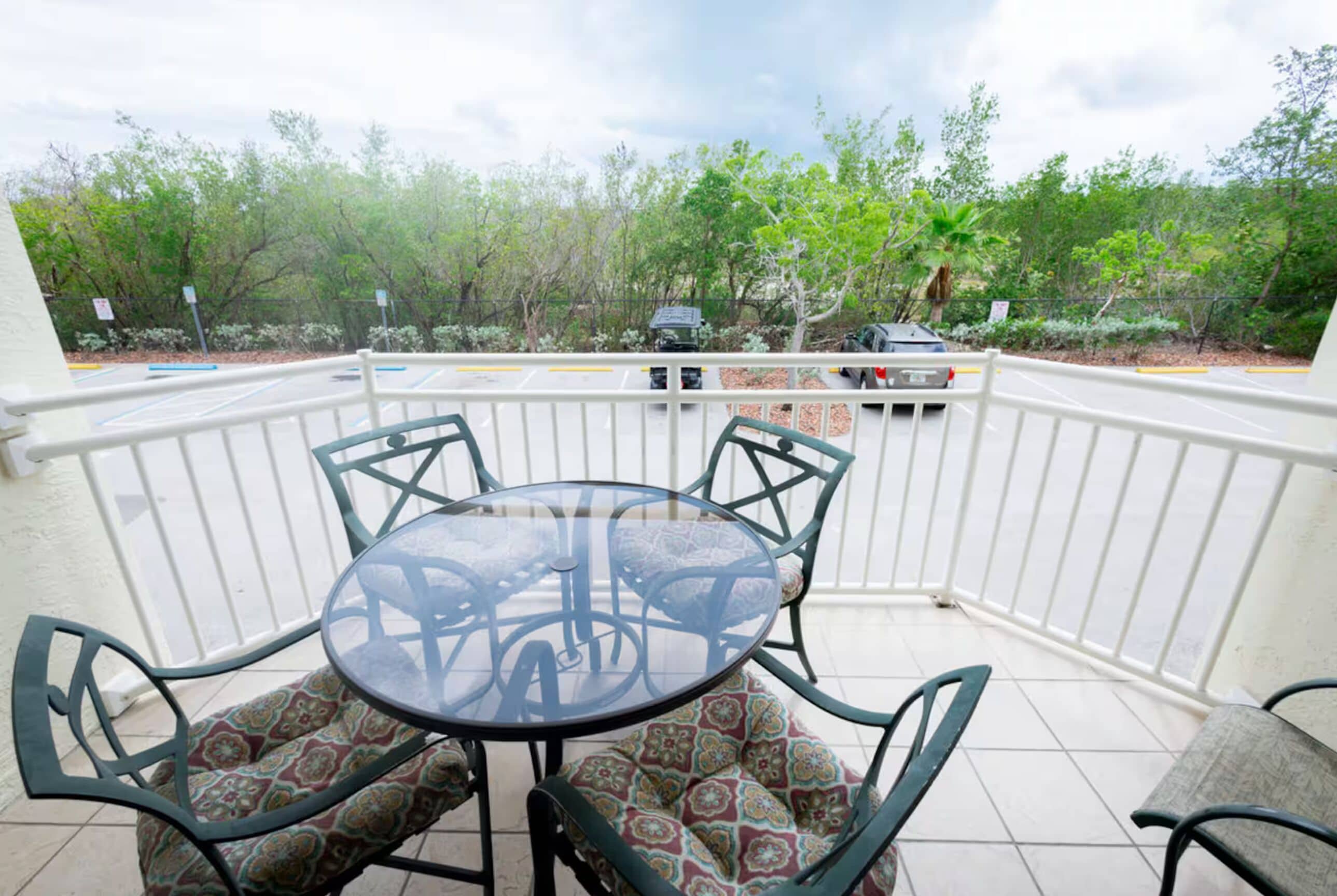 An outdoor patio with a round table and four chairs, surrounded by a white railing.