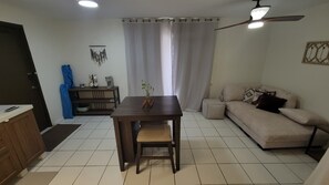 A living room with a sofa, a dining table with chairs, a ceiling fan, and a window with curtains. - URBAN OASIS GARDEN ARUBA
Lovely studio with AC in Oranjestad (Oranjestad)