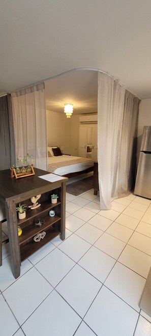 A compact hotel room with a bed, a small desk, a chair, a wardrobe, and a refrigerator. - URBAN OASIS GARDEN ARUBA
Lovely studio with AC in Oranjestad (Oranjestad)