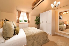 Ein Schlafzimmer mit einem Bett, einem Heizkörper, einem Fenster mit Vorhängen, einer Pflanze, einem Kleiderschrank und einem Spiegel, der ein Bett reflektiert.