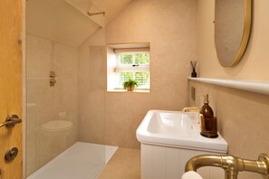 Ein Badezimmer mit Dusche, Toilette, Waschbecken und Fenster.
