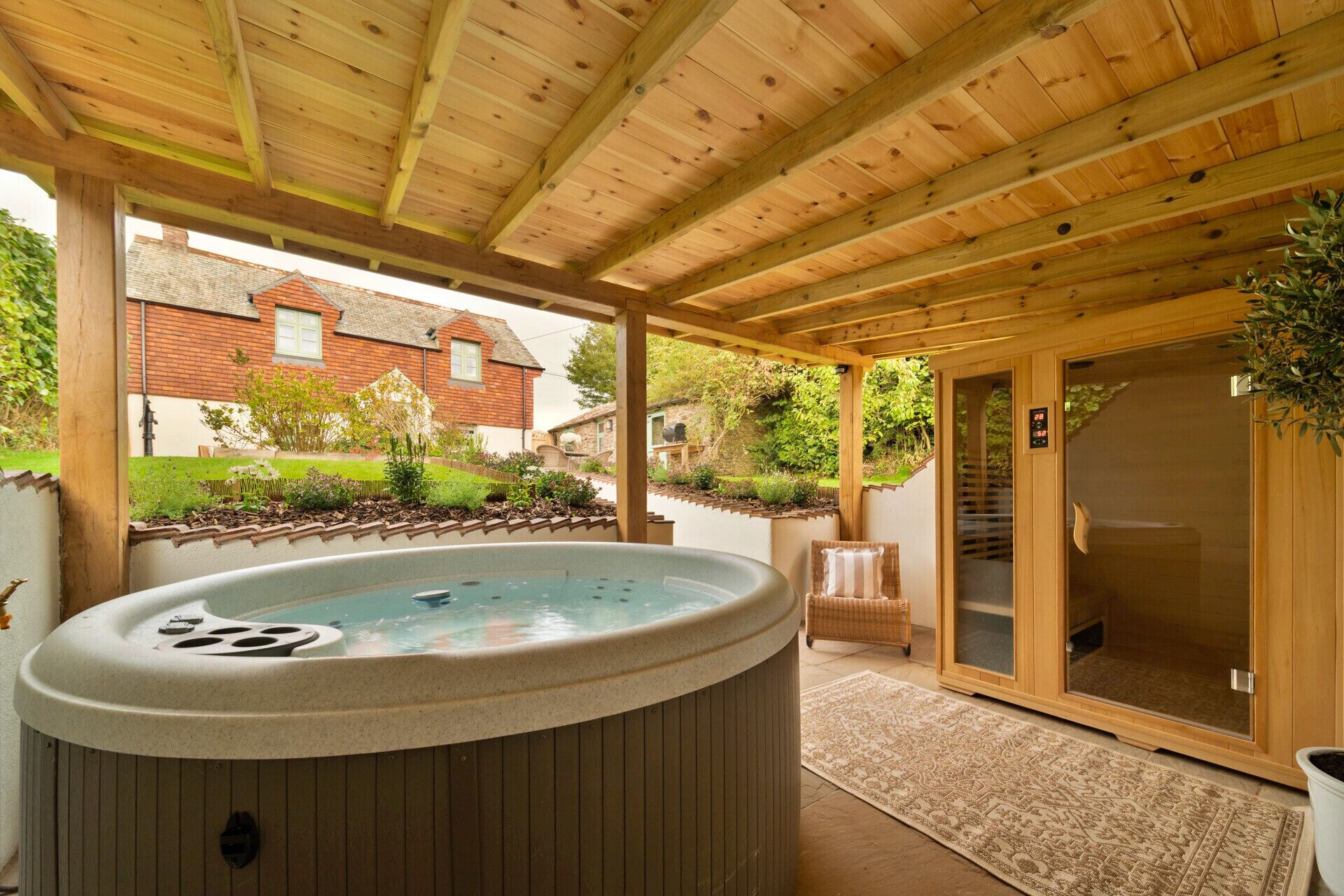 Un bain à remous sous une pergola en bois, avec vue sur une maison et un jardin.