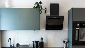 A modern kitchen with a built-in oven, a sink, and a countertop with a kettle and other items. - Lumé06.... (Wirges)