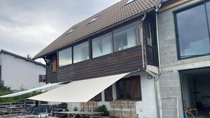 Een modern huis met een groot terras, tuinmeubilair en een overdekte patio.