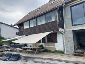 Uma casa moderna com um amplo deck, móveis para área externa e um espaço coberto de varanda.