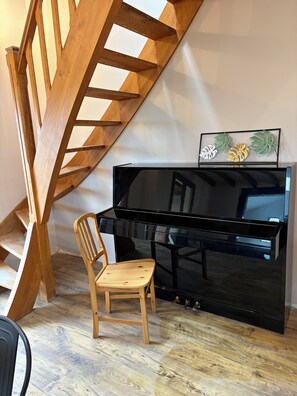 Eine Holztreppe mit einem schwarzen Klavier und einem Holzstuhl in einem Raum mit Holzboden.