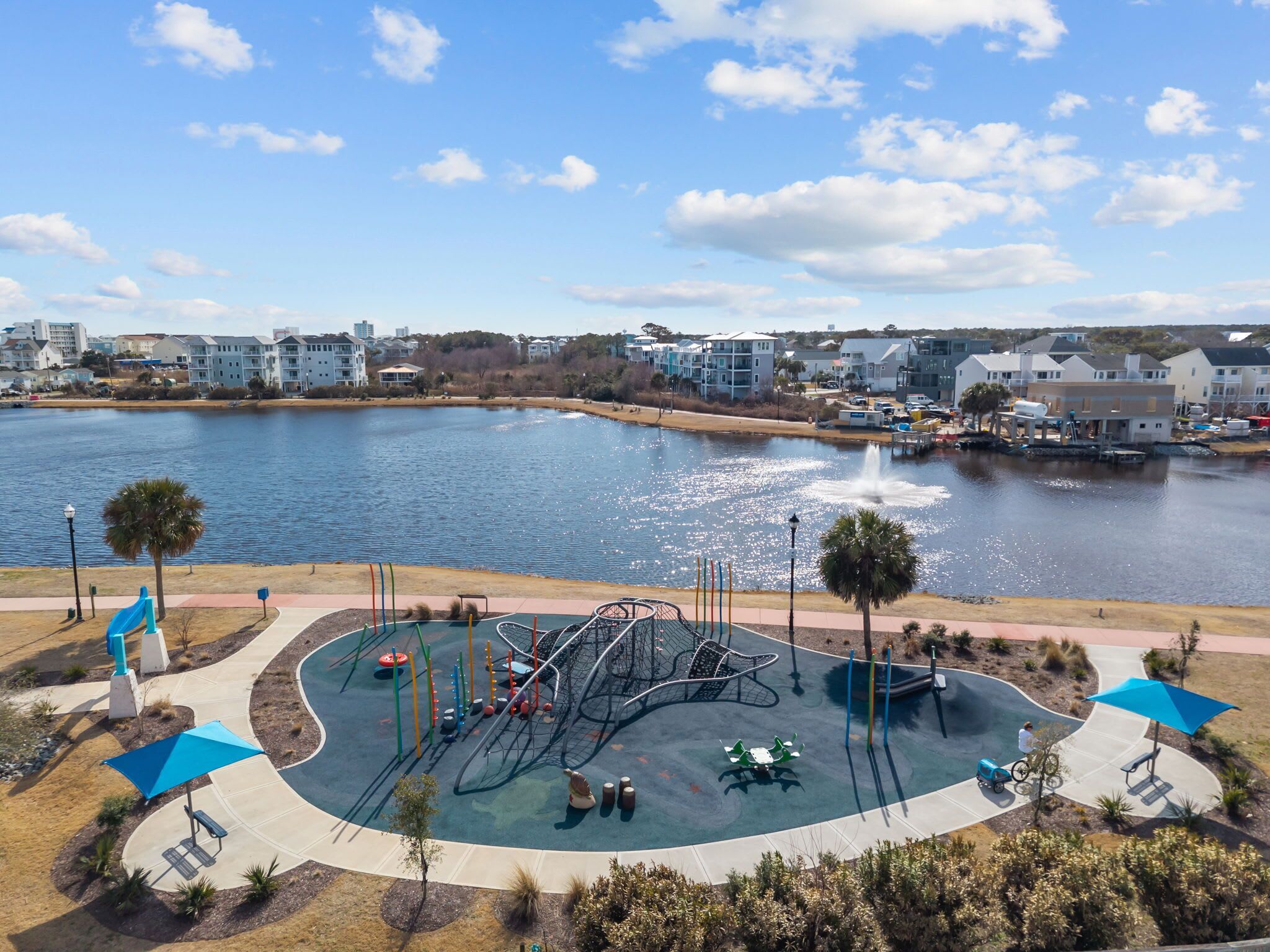A waterfront park with playground equipment and a fountain.