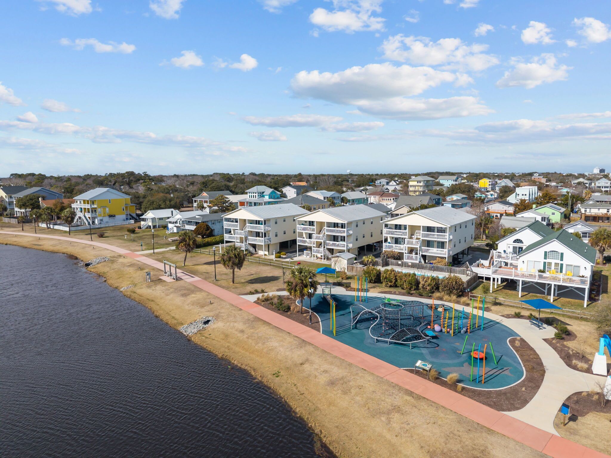 A coastal residential area with a swimming pool, beachfront, and multi-story buildings.
