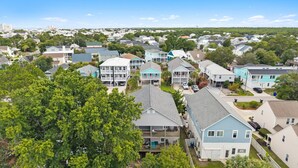 A residential area with houses, some with balconies, and a dense tree line in the foreground. - Coco Beach - Walk to Carolina Beach, Family Friendly Townhome (Carolina Beach)