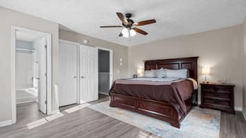 A bedroom with a bed, nightstands, a ceiling fan, and a walk-in closet.