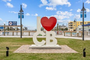 Ein öffentlicher Park mit einer großen herzförmigen Skulptur und den Buchstaben 'I' und 'CB' auf einer Ziegelplattform.
