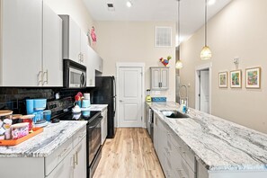 A modern kitchen with white cabinetry, a black refrigerator, and a marble countertop. - Brooklyn Arts Condo | Walk to Everything (Wilmington)