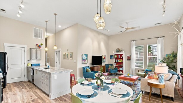 Una cocina moderna con una isla central, comedor con mesa y sillas redondas, y sala de estar con sofá y sillas.