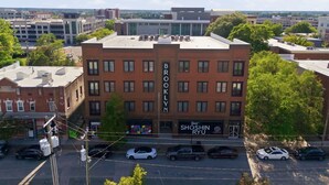Un edificio de varios pisos con el nombre 'BROOKLYN' en la fachada, rodeado de otros edificios y árboles.