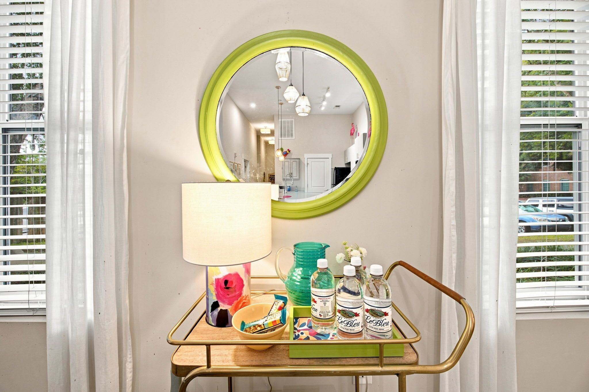 A room with a mirror, a lamp, a tray with bottles, and a bowl.