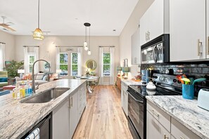 A modern kitchen with a central island, stainless steel appliances, and a view of the outdoors. - Brooklyn Arts Condo | Walk to Everything (Wilmington)