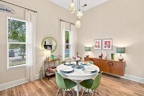 A dining area with a round table, chairs, a buffet, and artwork on the wall. - Brooklyn Arts Condo | Walk to Everything (Wilmington)