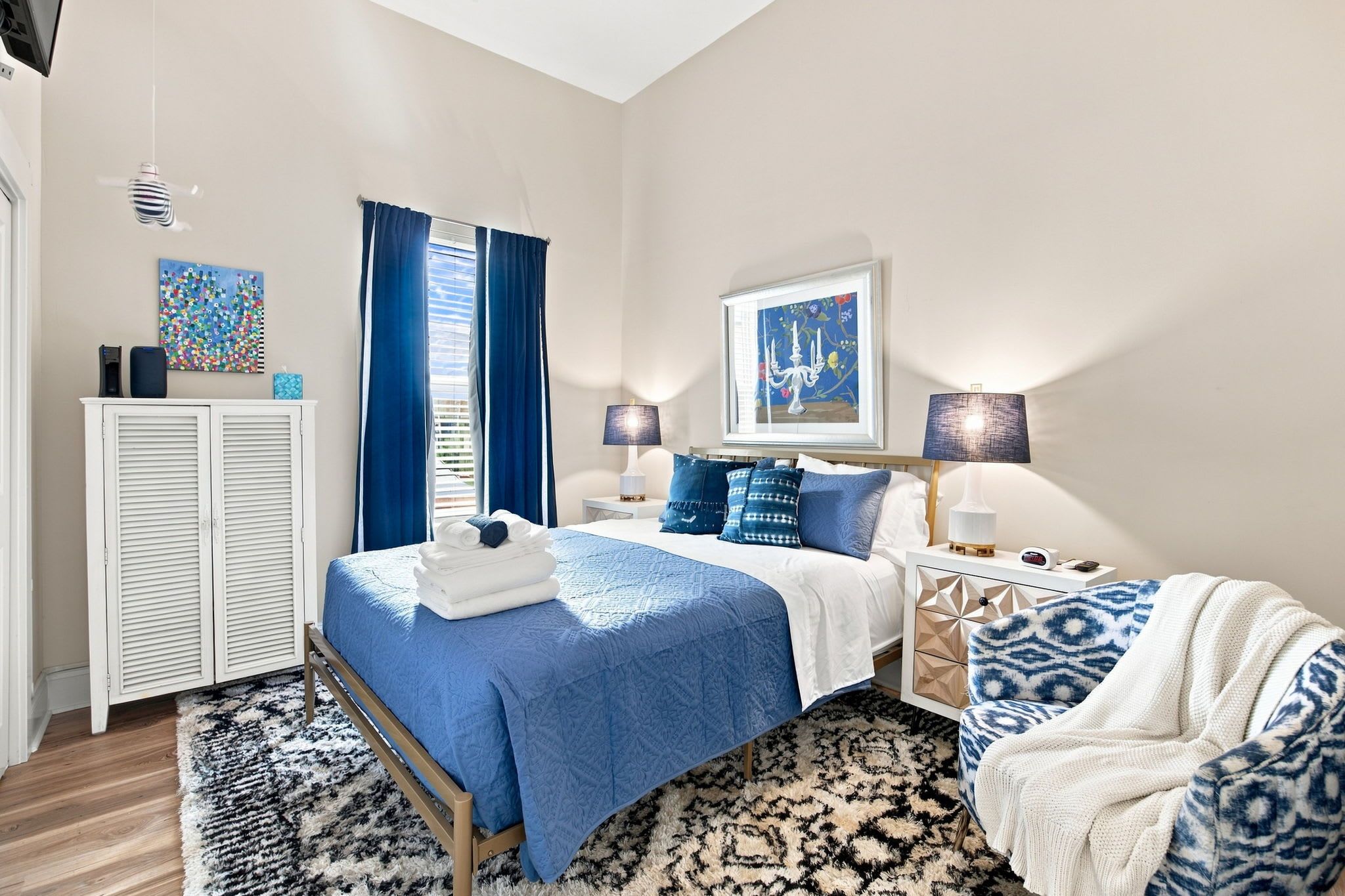A bedroom with a bed, bedside tables, a wardrobe, and artwork on the walls.