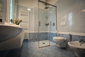 Une salle de bain avec une douche à parois de verre, des toilettes et deux lavabos.