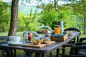 An outdoor picnic setup with a table, food, and a view of a forest. - B&B La Tana de Lupo - Triple Room with Private Bathroom: Comfort & Nature (Savigno)
