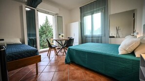 A hotel room with a bed, a desk, a chair, and a view of the outdoors. - Vrbo Property (Savigno)
