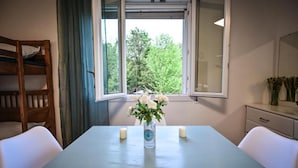 Een kamer met een tafel, een raam, een bed en een spiegel.