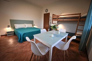 Ein Zimmer mit einem Bett, einem Tisch mit Stühlen, einem Etagenbett und einer Tür.