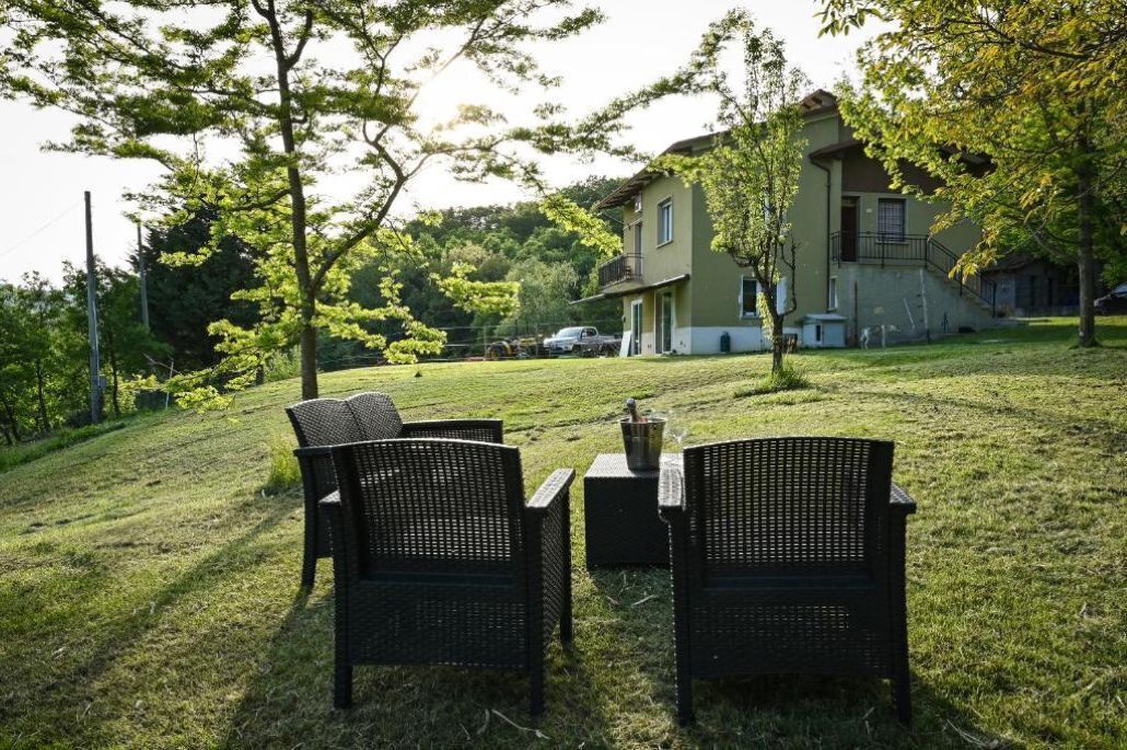 Un espace extérieur verdoyant, avec des meubles en osier et un bâtiment en arrière-plan.