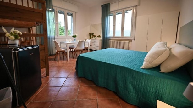 Een slaapkamer met een bed, een bureau, een stoel en een radiator.