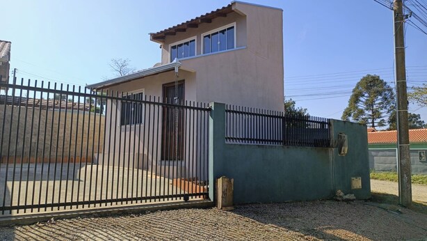 A gated property with a single-story building, a paved driveway, and a metal fence. - Apto Econômico Mafra  (Mafra)