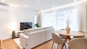 Ein modernes Wohnzimmer mit einer Couch, einem Fernseher und einem Essbereich.