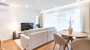 Een moderne woonkamer met een bank, televisie en eethoek.