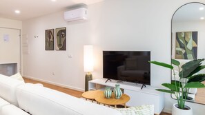 A modern living room with a flat-screen TV, white sofa, and two striped vases on a wooden table. - Polacos Residence | 1BR | Apt M by LovelyStay (Vila Nova de Gaia)