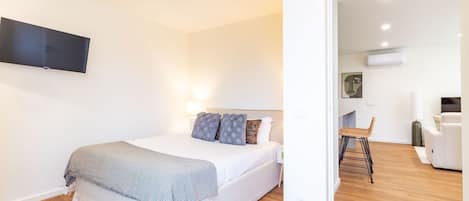 Une chambre à coucher avec un lit, des oreillers, une télévision et une chaise.