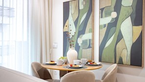 A dining area with a round table, chairs, a vase with dried flowers, and abstract paintings on the wall. - Polacos Residence | 1BR | Apt M by LovelyStay (Vila Nova de Gaia)