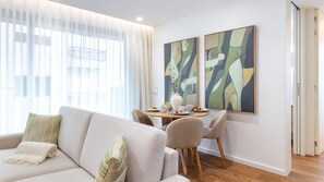 A modern living room with a sofa, a dining table with chairs, and abstract art on the wall. - Polacos Residence | 1BR | Apt M by LovelyStay (Vila Nova de Gaia)