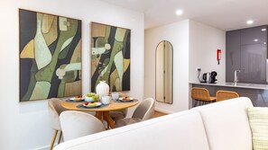 A modern living room with a dining area, featuring abstract artwork, a round dining table, and a sofa. - Polacos Residence | 1BR | Apt M by LovelyStay (Vila Nova de Gaia)