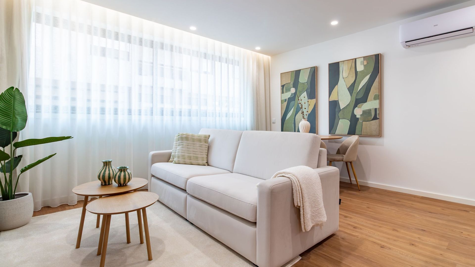 Uma sala de estar moderna com um sofá, uma mesa de centro e um espaço de jantar com cadeiras.