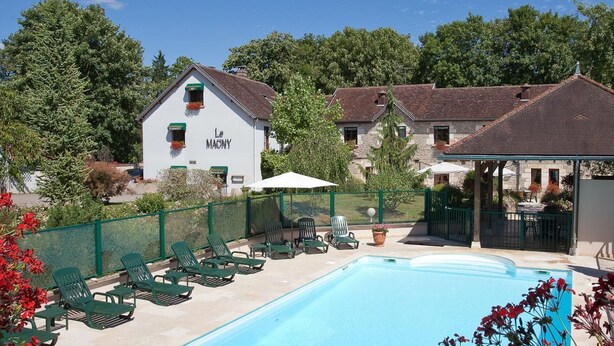 A pool area with lounge chairs, a building labeled 'Le MACNY,' and a fenced garden. - restaurant hôtel le magny (Les Riceys)