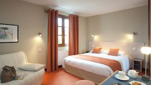 A hotel room with a bed, a chair, a table with a cup and cookies, and a window with curtains. - restaurant hôtel le magny (Les Riceys)