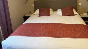 A hotel room with a large bed, two pillows, a nightstand, and a water bottle. - restaurant hôtel le magny (Les Riceys)