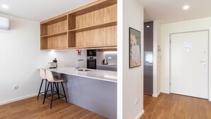Eine moderne Küche mit Holzschränken, einem Edelstahlkühlschrank und einer Bar mit Hockern.