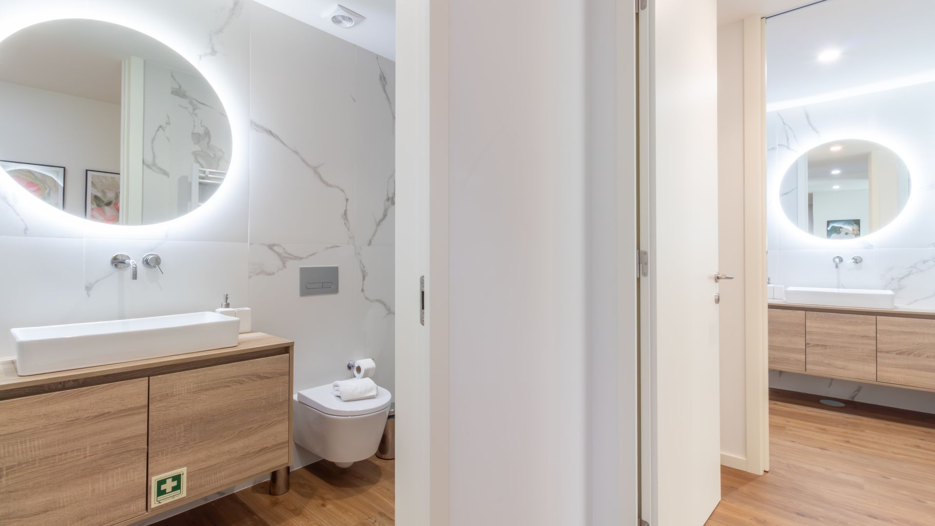 Et moderne badeværelse med vaskebord, toilet og et spejl med lys.