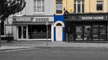 A street view with three commercial buildings: a Greek restaurant, a bookstore, and a show home.