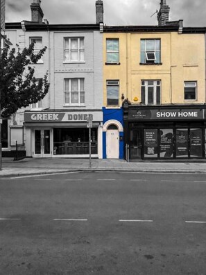 A street view with three commercial buildings: a Greek restaurant, a bookstore, and a show home. - Prince Of Wales Rd - Apartment 2 (Norwich)