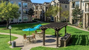 A courtyard with outdoor seating, a pergola, and stone buildings in the background. - Landing Chic 1bd, Clubhouse, Gym (Katy)