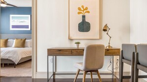 A bedroom with a bed, a desk with a chair, a framed picture, and a small plant. - Landing Chic 1bd, Clubhouse, Gym (Katy)