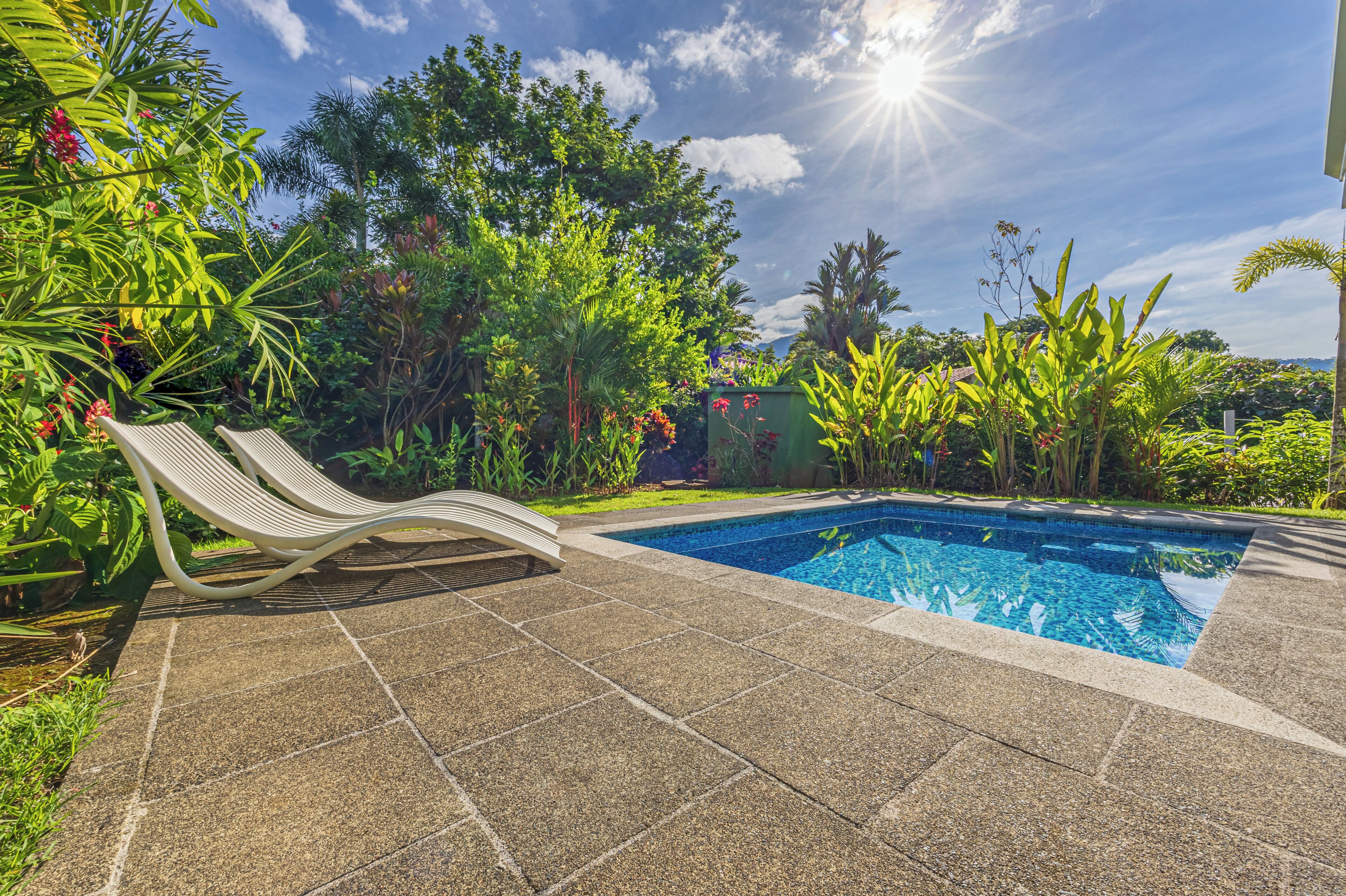 Una piscina con una terraza de baldosas y una tumbona.